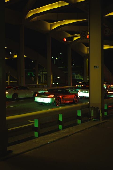 Cars on a road beneath a bridge illuminated in yellow