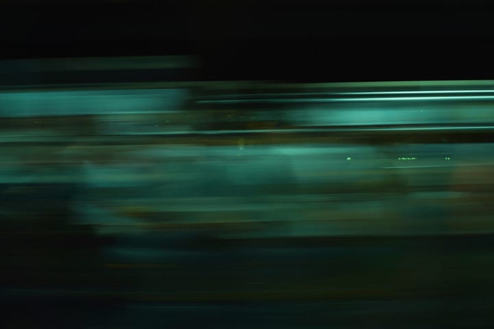 Green light streaks flowing horizontally through the dark