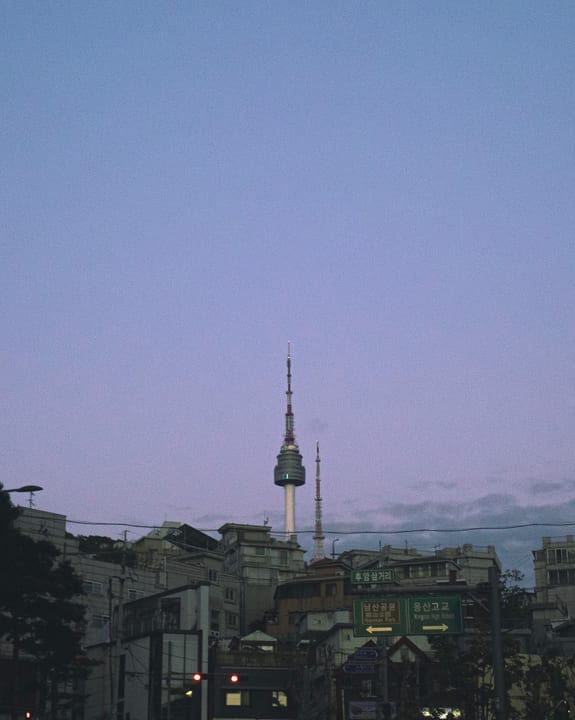 Namsan Tower and city buildings beneath a purple evening sky