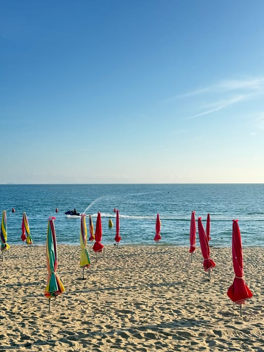 Rows of closed parasols on a sandy beach by the blue sea