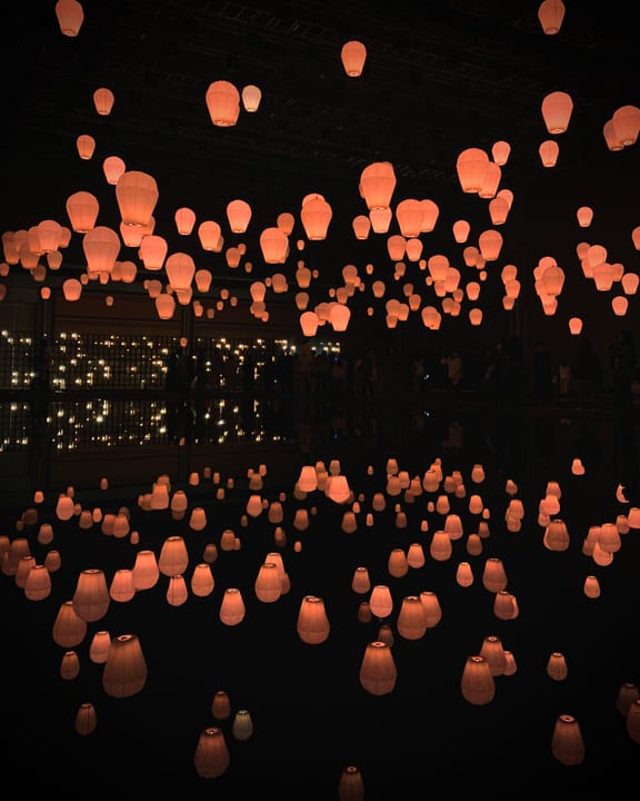 Orange lanterns and their reflections in a dark exhibition space